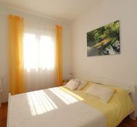 Bedroom in a family house with a bed, chair, and wooden decor flooring.