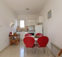 A dining room with red chairs and a white kitchen in a family house.