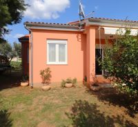 A family house in Vodice with a terracotta roof, surrounding greenery, and flower pots in the garden.