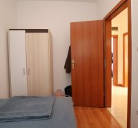 Bedroom in a family house with a bed, wardrobe, and wooden decor flooring.