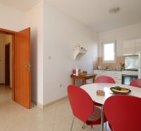 Dining room with a table and red chairs in a family house, light tiles.