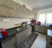 A kitchen in a 3-room apartment with appliances and a wooden decor floor.