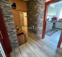 A hallway of a 3-room apartment with a wooden decor floor and stone-clad walls.