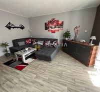 Living room in a three-room apartment with a wooden decor floor and a gray sofa.
