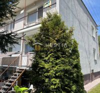 Apartment building in Brezová pod Bradlom with balconies and a staircase to the garden.