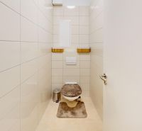 Bathroom in a 2-room apartment with white tiles and a toilet.