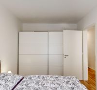 A bedroom in a two-room apartment with a white wardrobe and a bed with floral bedding.