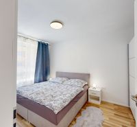 A bedroom with a double bed, a nightstand, and a wooden decor floor in a two-room apartment.