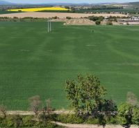 Green recreational lands near Trhovište with a view of the village and yellow fields.