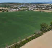 Vast green fields and Trhovište in the background, recreational plots in the surroundings.