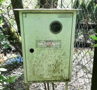 An electrical box in the garden in Hubina, overgrown with vegetation, overlooking the stream and the fence.