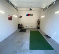In the garages, there is a green carpet, a shelf, and a decoration with a logo on the wall.
