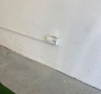 White wall with a socket and concrete floor in the garages on Kazanská Street.