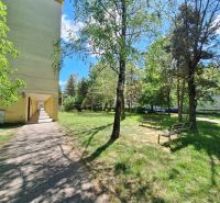 Path and benches surrounded by greenery near the apartment building on Železiarenská Street in Šaca.
