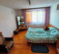 A room in a family house with a bed, an armchair, and a floor with a wooden decor.