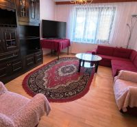 Living room with dark furniture, wood-patterned floor, red sofa set, and carpet.
