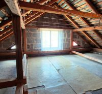 An attic with wooden beams in a family house, illuminated by a window.