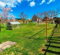 The garden of a family house in Jarabina with a wooden fence and a greenhouse.