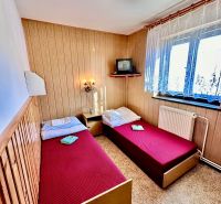 Wooden paneling with two beds, a television, and a window in a family house.