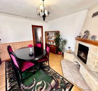 A dining room in a family house with a fireplace, furniture, and flooring with a wood decor.
