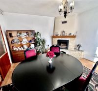 Dining room in a family house with a fireplace, black table, and a dish cabinet.