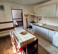 A kitchen in a family house with a dining table and a wooden decor floor.