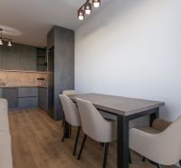 A kitchen in a 2-room apartment with cabinets, a table, and a wooden decor floor.