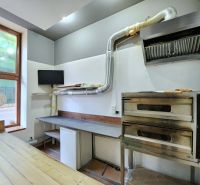 A bakery oven and a table with a hood in a gastro space on a floor with a wooden decor.