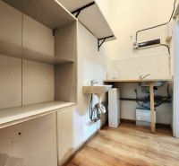 A kitchenette in gastro premises with shelves, a sink, and a floor with a wooden decor.