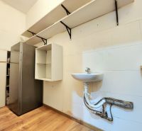 Gastro premises with a refrigerator, sink, shelves, and a floor with a wooden decor.