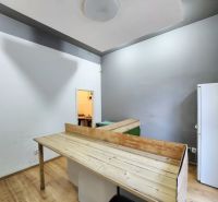 Interior of a gastro space with a wooden decor floor, table, and refrigerator.