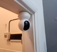 A security camera on the wall in the dining area, with electrical wiring underneath it.