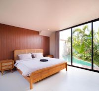Bedroom in a villa with a pool, wooden decor flooring, tropical garden.