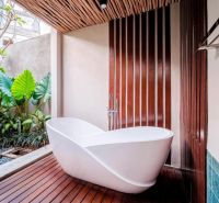White bathroom in a villa with leafy plants and wood-patterned floor.