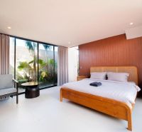 A bedroom in a villa with wooden decor, a bed, and large windows.