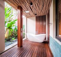 Luxurious bathroom in a villa with wooden decor and exotic plants.