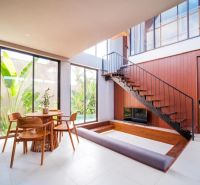 Space in the Villa with large windows, a wooden staircase, and a dining table.