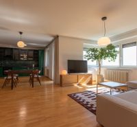 Living room in a 4-room apartment with a wood-patterned floor and furniture in the kitchen.