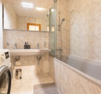 A bathroom with a bathtub, a mirror, and a washing machine in a 4-room apartment.