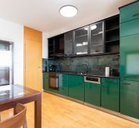 A kitchen with green cabinets, a dining table, and a wooden decor floor in a 4-room apartment.