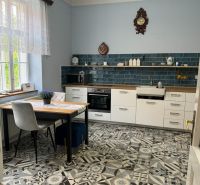 A kitchen in a family house with blue tiles and patterned flooring.