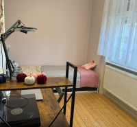 A room in a family house with a bed, a shelf, and a floor with a wooden decor.
