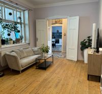 Living room in a family house with a wooden decor floor, plants, and a sofa.