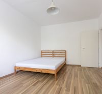 A bedroom with a bed and a wooden decor floor in a three-room apartment.
