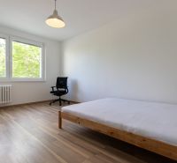 Bright bedroom in a 3-room apartment with wood-patterned flooring and large windows.