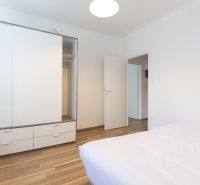 A bedroom in a 3-room apartment with a white wardrobe and a floor with a wooden decor.