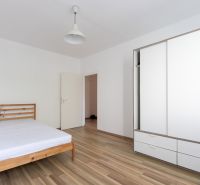 A bedroom with a wooden bed, a white wardrobe, and a floor with a wooden decor in a 3-room apartment.