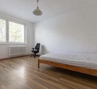 Bright bedroom with a bed and an office chair, floor with wood decor.