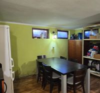 Interior of a cottage with a dining table, a wardrobe, and shelves, floor with wooden decor.