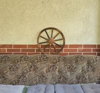 A comfortable sofa on the cottage veranda with wooden elements, a wheel on the wall.